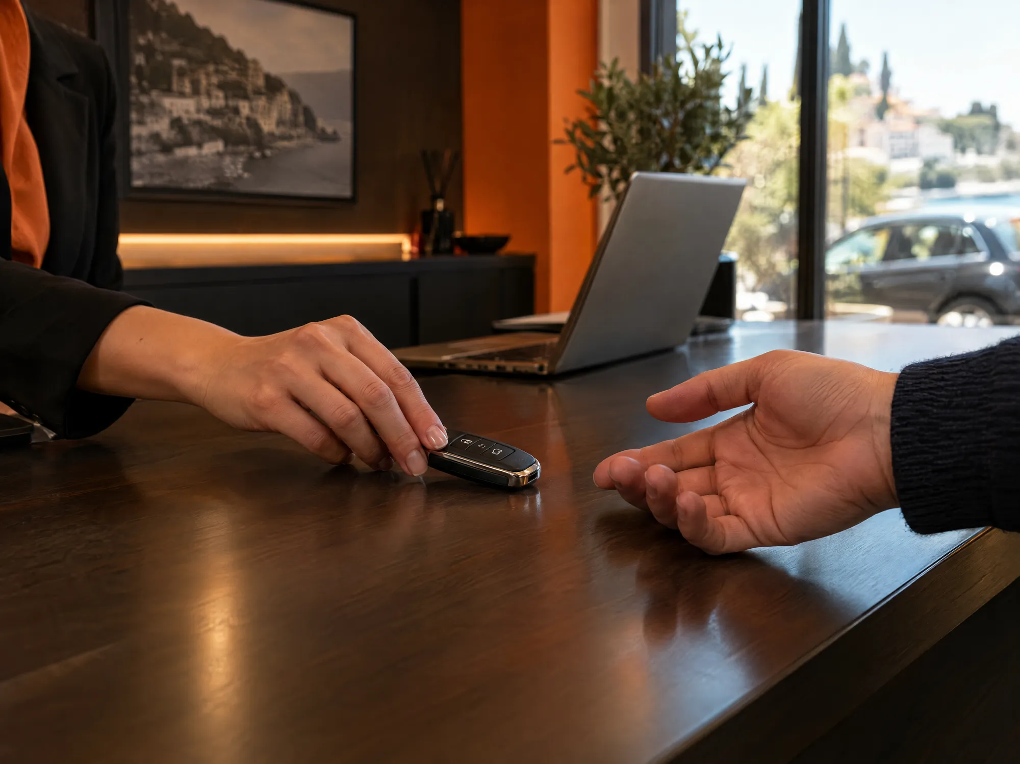 Al banco di un noleggio, una mano fa scivolare la chiave dell'auto verso il cliente